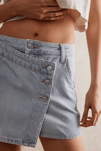 Gros plan sur un short en jean bleu clair avec braguette boutonnée asymétrique