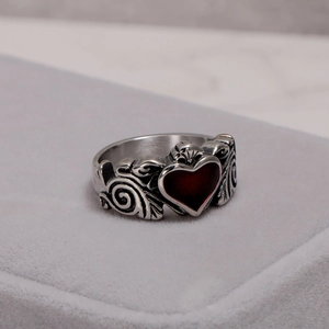 Polished silver Claddagh ring with a deep red heart on a grey velvet jewelry box
