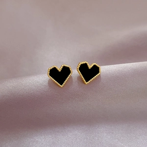 Dettaglio di orecchini a cuore in smalto nero con bordo perlato dorato sulla seta