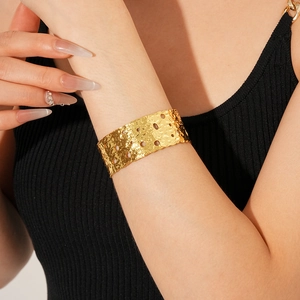 Detailed shot of gold-plated hollow cuff bracelet with hammered texture on a model wrist