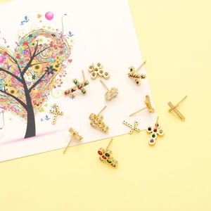 Macro shot of colorful zircon cross stud earrings with gold plating on a warm backdrop