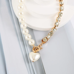Macro detail of asymmetric pearl and rhinestone necklace with golden heart and OT buckle