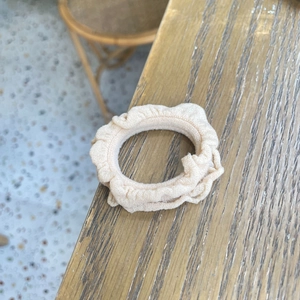 Minimalist beige ruffle fabric scrunchie with pleated texture on a wooden table