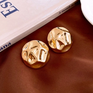 Detailed macro view of golden geometric earrings with vintage hammered metal texture