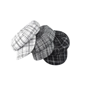 Detail showing white, gray, and black plaid tweed newsboy caps with vintage texture