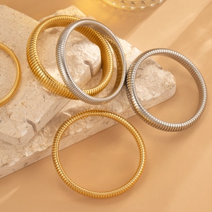 Nahaufnahme flexibler Edelstahl-Armreifen mit Schlangenknochen-Textur in Gold und Silber