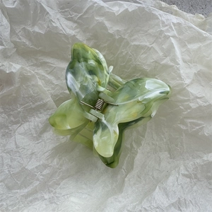 Dettaglio del fermaglio per capelli a farfalla con motivo marmorizzato verde e bianco