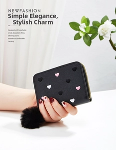 Detail of short leather wallet with embroidered hearts and black pompom keychain charm