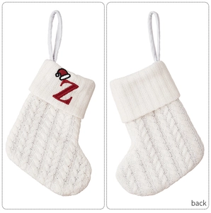 Detail of white cable knit Christmas stocking with red embroidered letter Z and mini hat