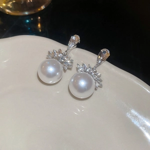 Gros plan de boucles d'oreilles perles avec zircons marquise sur plateau céramique
