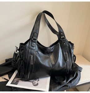 Detailed view of black tote bag featuring multi-zipper pockets and glossy leather texture