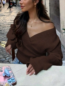 Detail of dark brown V-neck off-shoulder knitted sweater on a street fashion model