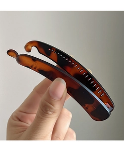 Detailed view of matte amber leopard print banana hair clip for a volumized ponytail