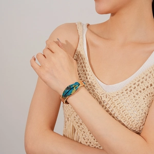 Detail of bohemian gold beaded cuff bracelet with blue and yellow floral silk fabric inlay