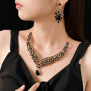 Detail of V-shaped gold necklace set with black gemstones worn by a model