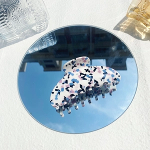 Detail of large acetate hair claw clip with colorful terrazzo pattern on mirror