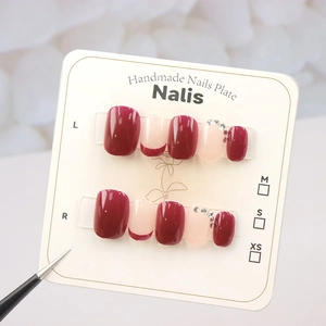 Detailed view of burgundy and pink press-on nails with sparkling rhinestones on display card