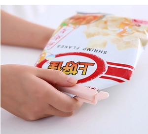 Close-up of hands applying a pink plastic sealing clip on a snack bag for freshness