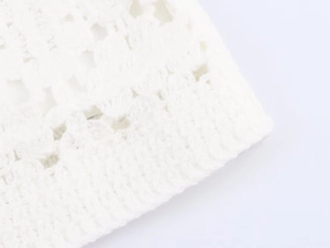 Close-up detail of white crochet knit fabric showing intricate hollow floral patterns