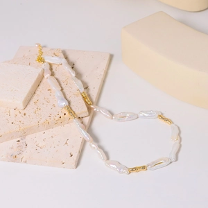 Baroque pearl necklace with textured gold beads on travertine stones in a still life view