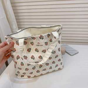 Detailansicht der cremefarbenen Canvas-Tasche mit rotem Blumenmuster und Reißverschluss