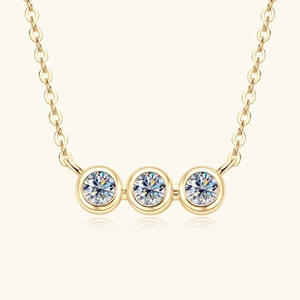 Close-up of triple round-cut moissanite stones on a gold-plated S925 silver necklace