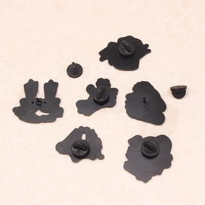 Detail view of various black metal enamel pin backs with secure butterfly clutch fasteners