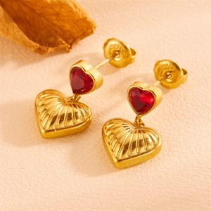 Macro view of gold heart drop earrings with red zircon and vertical textured relief