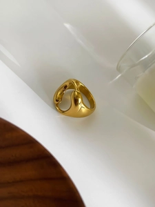 Dettaglio anello dorato fluido irregolare su supporto bianco con ombre eleganti