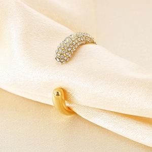 Detailed close-up of gold open ring with sparkling diamond inlay on silk fabric