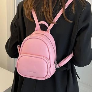 Stylish pink mini backpack for women made of premium PU leather on a black suit jacket
