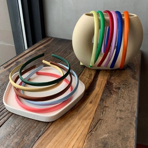 Slim satin headbands set in various jelly colors displayed on a white tray