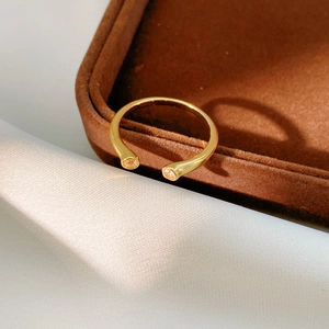 Détail d'une bague ouverte plaquée or 18k avec deux zircons sur velours brun