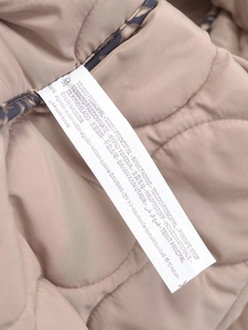 Détail de l'étiquette d'entretien interne montrant 100% coton sur la veste matelassée