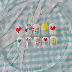 Detailed view of handmade press-on nails featuring 3D hearts and colorful plaid patterns