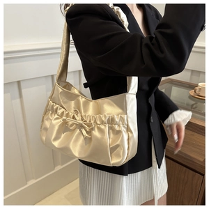 Detail of champagne pleated nylon shoulder bag with elegant bow knot on a model