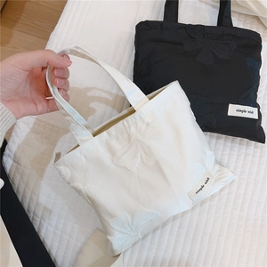 Detailed view of mini jacquard tote bags with 3D bow patterns in black and white colors
