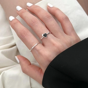 Close-up of stacked silver heart ring and bamboo band on finger with elegant suit