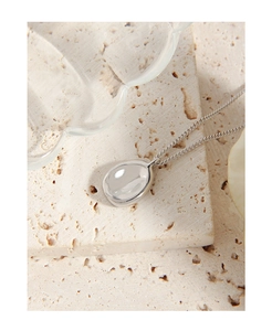 Detailed close-up of a minimalist S925 sterling silver oval pendant on textured rock