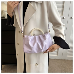 Detail of lavender pleated cloud bag with white pearl handle and gold metal hardware