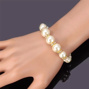 Elegant pearl bead bracelet featuring gold rhinestone spacers worn on a wrist