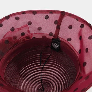 Detail view of red polka dot organza sun hat with spiral woven texture and brand label