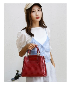 Detailed view of large red woven texture tote bag with glossy patent leather finish