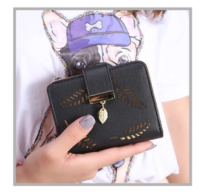 Close-up of black leather wallet featuring hollow leaf pattern and gold pendant detail
