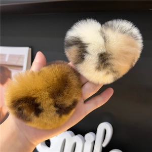 Close-up of fluffy heart-shaped leopard print hair clips in brown and beige tones