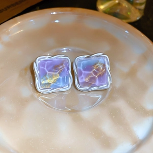 Close-up of square silver stud earrings featuring purple and blue marbled resin inlay