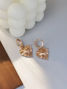 Dettaglio di orecchini a cuore in oro rosa S925 con texture a pieghe radianti particolari