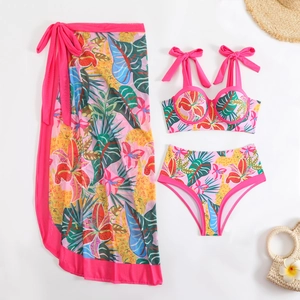 Flat lay of pink floral three-piece bikini set with tropical print mesh sarong skirt