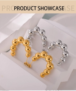 Detail shot of C-shaped ball stud earrings in gold and silver finish with mirror reflection