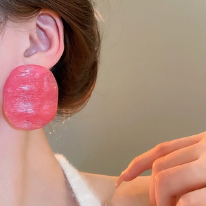 Close-up of pink oversized irregular round resin earrings with brushed texture on model